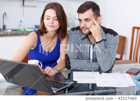 Young man and woman talking while looking at laptop together Young man and woman talking while looking at laptop together 43527460