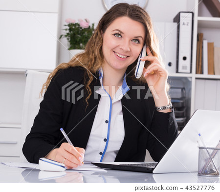 Bussineswoman filling up documents and talking on the phone Bussineswoman filling up documents and talking on the phone 43527776