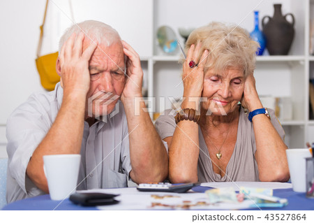 Worried mature man and woman analyzing bills Worried mature man and woman analyzing bills 43527864