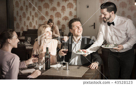 Waiter bringing delicious salads to visitors of restaurant Waiter bringing delicious salads to visitors of restaurant 43528123