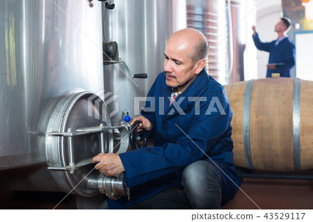 Smiling man machinery operator working in winery Smiling man machinery operator working in winery 43529117