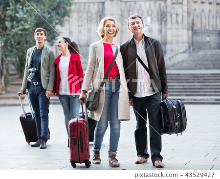 Two couples with baggage sightseeing and smiling Two couples with baggage sightseeing and smiling 43529427