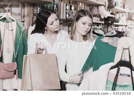 Young smiling female friends choosing fashion green pullover Young smiling female friends choosing fashion green pullover 43529538