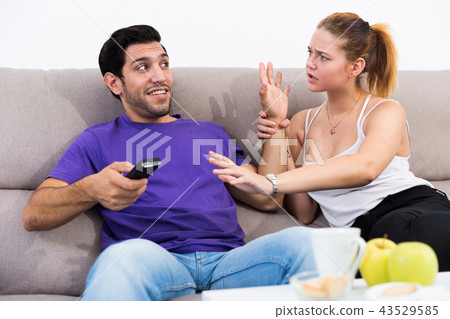 Woman trying to take away TV remote from boyfriend 43529585