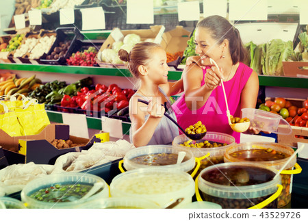 mother with girl picking olives in food shop . mother with girl picking olives in food shop . 43529726