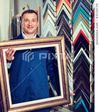 Man worker holding picture frame details on counter Man worker holding picture frame details on counter 43529729