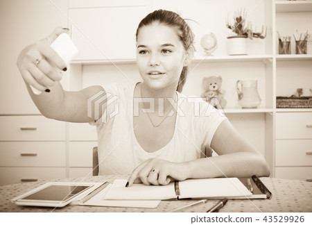 girl school pupil taking self portrait on smartphone while studying indoors 43529926