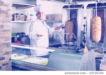 mature chef slicing kebab in fast food. 43530144