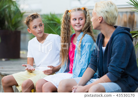 Smiling girl with boys discussing outdoors Smiling girl with boys discussing outdoors 43530170