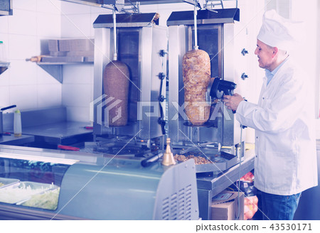 mature chef slicing kebab in fast food. 43530171