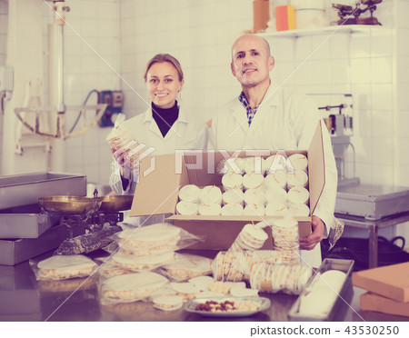 Different aged couple standing with box of turron in production workshop 43530250