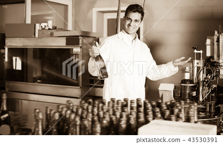 Adult male holding newly produced bottle of wine Adult male holding newly produced bottle of wine 43530391