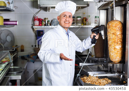 Cheerful mature man cook cutting kebab meat on kitchen 43530458