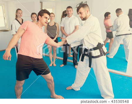 man training new taekwondo holds with adults during class man training new taekwondo holds with adults during class 43530548