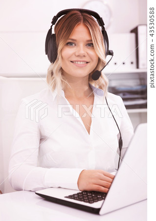 Young call center employee in headphones is sitting near laptop 43530588