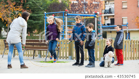 Children playing rubber band jumping game and laughing Children playing rubber band jumping game and laughing 43530745