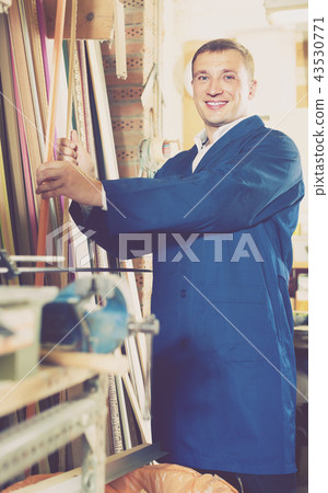 portrait of man in uniform choosing framing moulding in studio portrait of man in uniform choosing framing moulding in studio 43530771