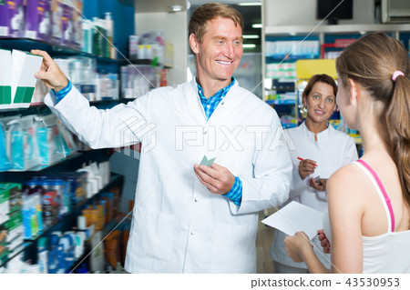 Smiling pharmacist helping customers Smiling pharmacist helping customers 43530953
