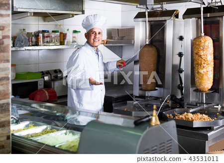 man chef wearing uniform cutting meat for kebab on kitchen in fast food restaurant 43531011