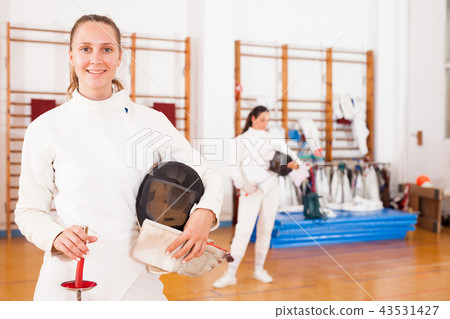 Smiling young female in uniform standing at fencing room Smiling young female in uniform standing at fencing room 43531427
