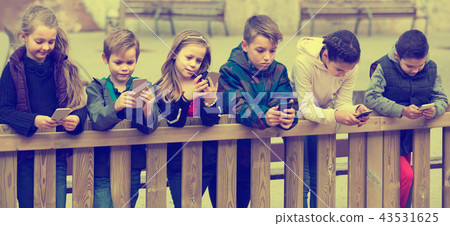 Outdoor portrait of girls and boys playing with phones 43531625
