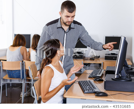 Teacher helping female student in computer class 43531685