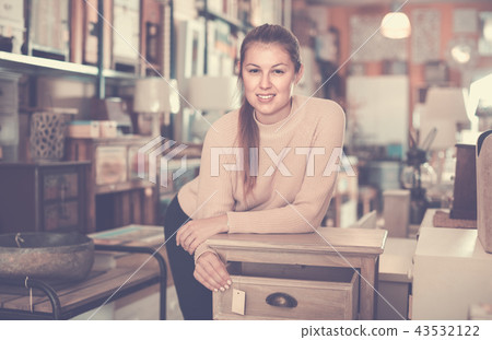 Woman buyer standing in furniture shopping room near chest of drawers Woman buyer standing in furniture shopping room near chest of drawers 43532122
