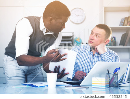 Two men in office working at laptop and documents Two men in office working at laptop and documents 43532245