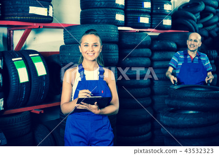 Portrait of mechanic girl in coveralls having cardboard with documents in hands Portrait of mechanic girl in coveralls having cardboard with documents in hands 43532323