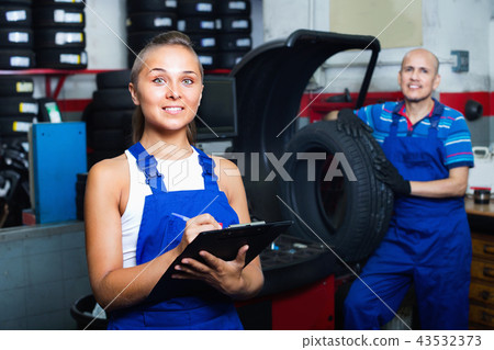 Portrait of mechanic girl in coveralls having cardboard with documents in hands 43532373