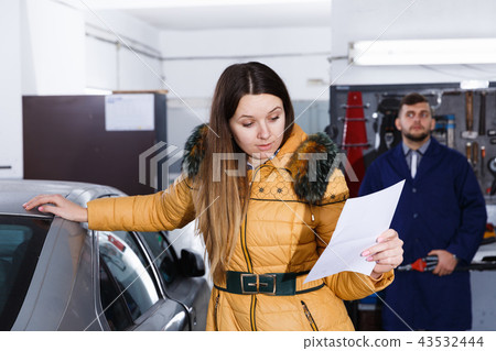 Young woman is disappointed of tire replacement of her car in winter Young woman is disappointed of tire replacement of her car in winter 43532444