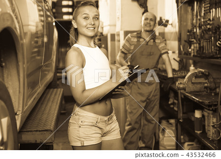 Woman standing and writing down data at car service Woman standing and writing down data at car service 43532466