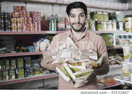 Smiling male is posing with purchases near shelves in supermarket. 43532667