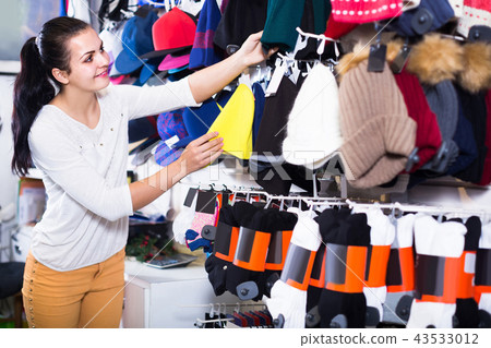 girl deciding on warm hat in sports store girl deciding on warm hat in sports store 43533012