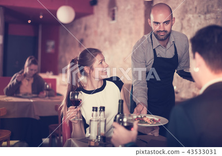 waiter bringing ordered dishes to smiling couple waiter bringing ordered dishes to smiling couple 43533031