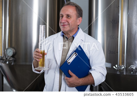 Man expert with folder is analizying the quality of beer in flask 43533605
