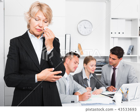 Business woman crying in office with working colleagues Business woman crying in office with working colleagues 43533693