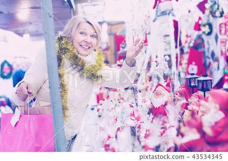 Mature woman choosing decorations at Christmas market Mature woman choosing decorations at Christmas market 43534345