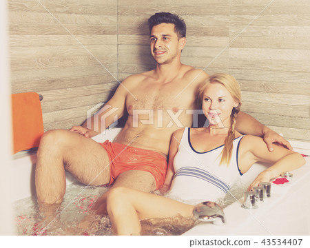 Young male with female are talking in bath with red petals Young male with female are talking in bath with red petals 43534407