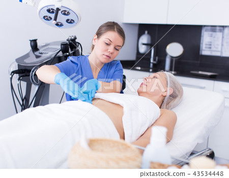 Cosmetologist examining mature female body Cosmetologist examining mature female body 43534448