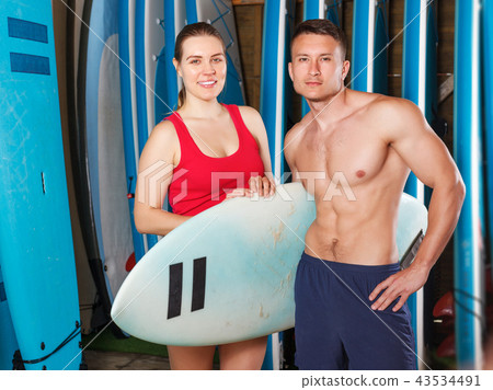 sporty couple with surf equipment in surf club sporty couple with surf equipment in surf club 43534491