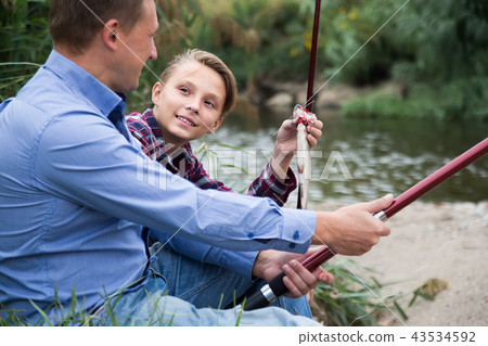 Portrait of smiling father with son having fish Portrait of smiling father with son having fish 43534592