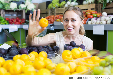 young woman buying plums at market. 43534790