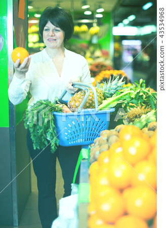 Middle aged woman with basket choosing fruits 43534968
