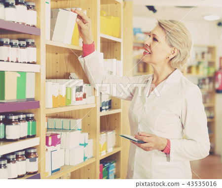 Aged female seller is checking assortment 43535016