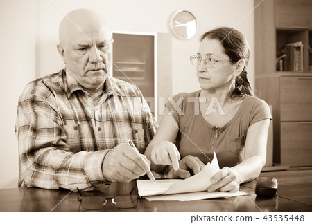 serious mature couple fills in questionnaire 43535448