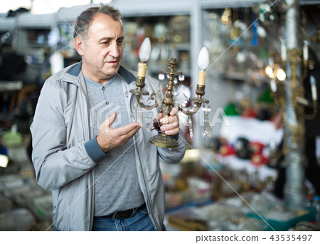 Adult male is choosing lamp at the market of old things. 43535497