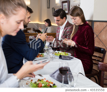 Modern young people with phone at restaurant Modern young people with phone at restaurant 43535550