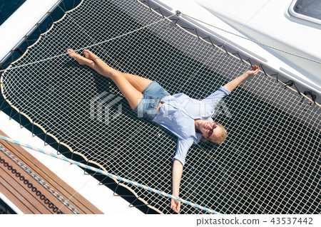 Woman relaxing on a luxury catamaran sailing boat. Woman relaxing on a luxury catamaran sailing boat. 43537442