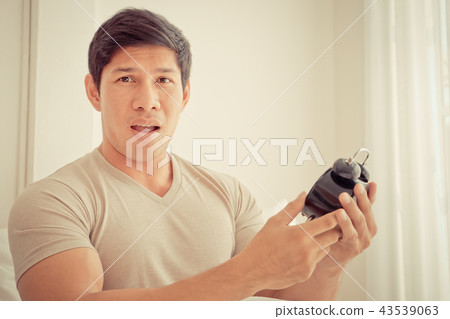 Casual man is surprise on late alarm clock time 43539063